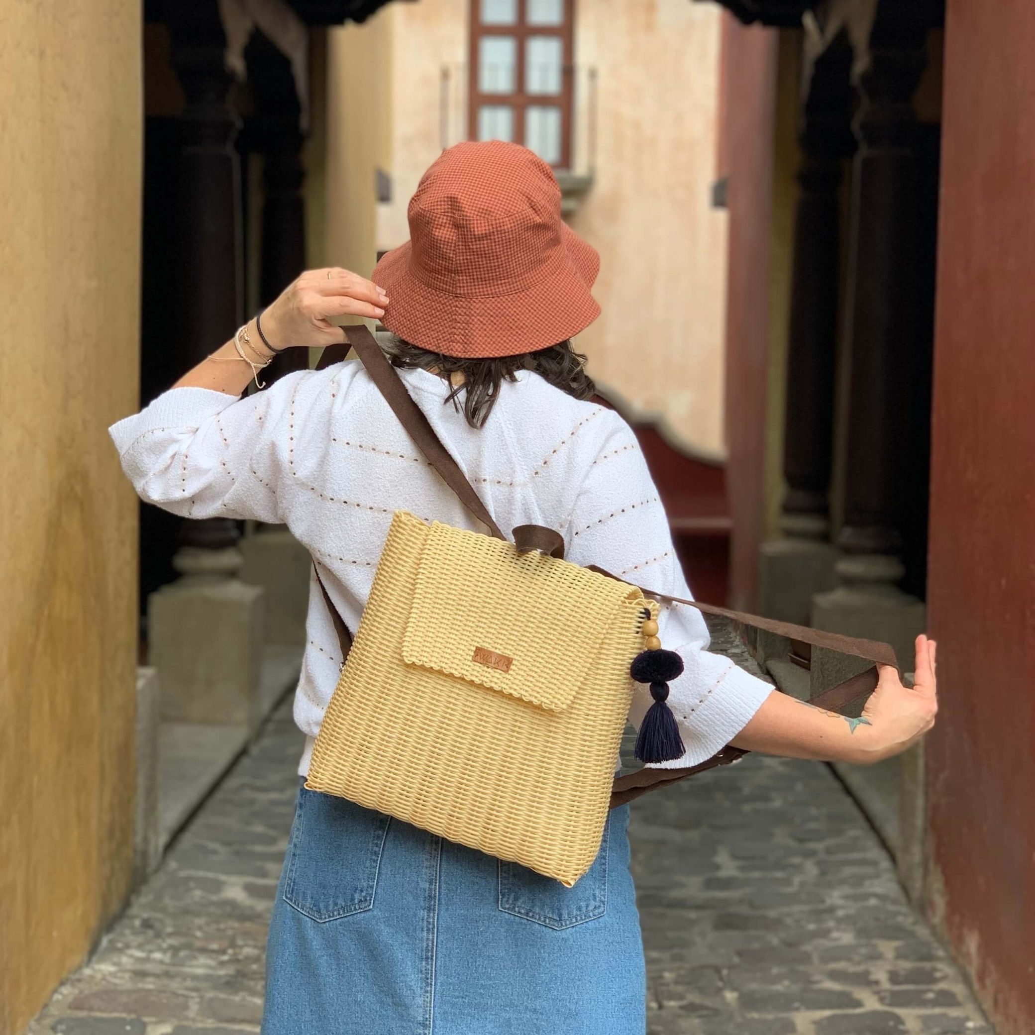 Persona sosteniendo una bolsa BACKPACK palorosa con pompón corinto y correas ajustables.